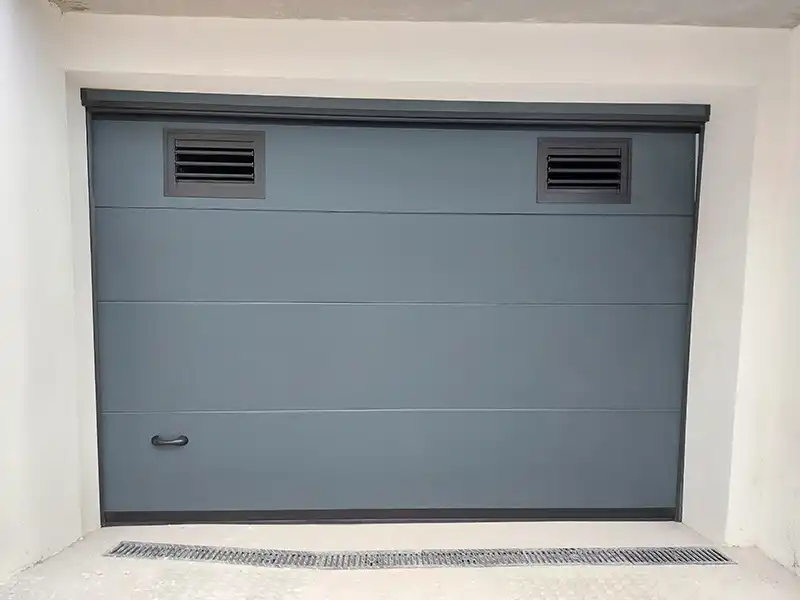 Puerta automática seccional gris antracita con rejillas de ventilación superiores